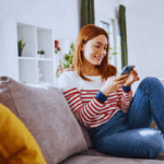 Young woman smiling while reading relationship text messages on her phone during an online chat.