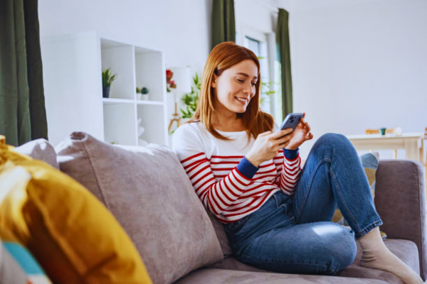 Young woman smiling while reading relationship text messages on her phone during an online chat.