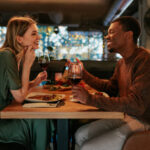 A happy couple enjoying a romantic dinner together, laughing and sharing what to talk about on a date over drinks.