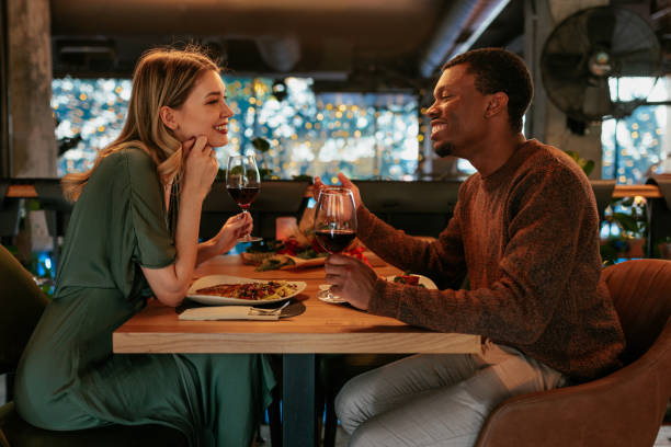 A happy couple enjoying a romantic dinner together, laughing and sharing what to talk about on a date over drinks.